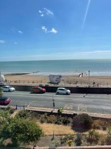 un aparcamiento junto a una playa con coches aparcados en "The Parlour" Seafront Apartment, en Eastbourne