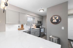 布兰森Hadley's Place at Pointe Royale, Pristine 2 Bed 2 Bath Condo的厨房里有白色的橱柜，墙上挂着一个钟