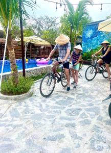 Cái Răng的住宿－Bến Đò Xưa Homestay & Coffee，一名男子和一名儿童骑着自行车在游泳池旁边