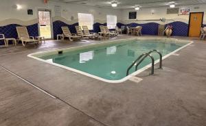 einen Pool in einem Zimmer mit Stühlen und Tischen in der Unterkunft Baymont by Wyndham Noblesville in Noblesville