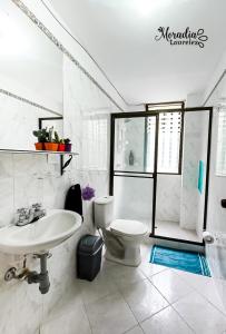 a white bathroom with a sink and a toilet at Moradia Laureles Medellin in Medellín