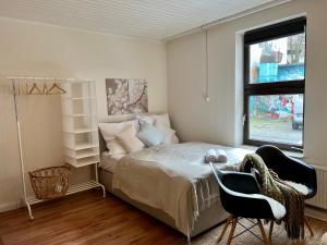 a bedroom with a bed and two chairs and a window at Gemütliches Apartment im Viertel mit Flair - Zentral in Bremen