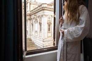 a woman looking out a window at a building at The Major Hotel in Rome