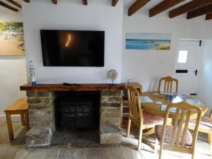 a living room with a fireplace and a tv on a wall at Staddlestones Cottage in Bridport