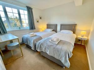 a bedroom with two beds and a desk and windows at Bay tree Cottage Hemsley in Helmsley