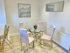 a dining room with a glass table and pink chairs at Bay tree Cottage Hemsley in Helmsley