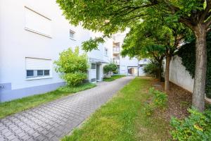 a walkway between two white buildings with trees at Minty Lounge in Ludwigshafen am Rhein