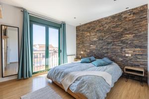 a bedroom with a brick wall and a bed with blue pillows at Cozy apartment in Las Gabias with a great terrace in Las Gabias