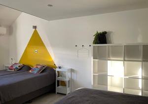 - une chambre avec un lit et une pyramide jaune sur le mur dans l'établissement Arcaden, à Sint-Martens-Voeren