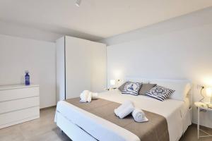 een witte slaapkamer met een groot bed met handdoeken erop bij Amazing View - Exclusive Apartment Portu Frailis in Àrbatax