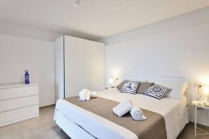 Un dormitorio blanco con una cama grande con toallas. en Amazing View - Exclusive Apartment Portu Frailis, en Àrbatax