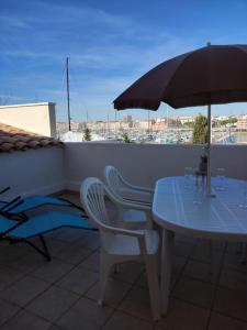 a table and chairs with an umbrella on a balcony at Vacances Ambassades du Soleil in Cap d'Agde