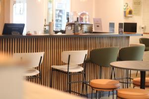 un restaurant avec des chaises et des tables devant un comptoir dans l'établissement Campanile Melun Sénart, à Vert-Saint-Denis