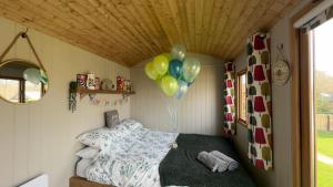 a room with a bed with balloons and a ceiling at Shepherds Hut at Cedar Gables in Lamberhurst