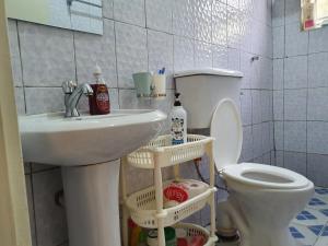 La salle de bains est pourvue d'un lavabo blanc et de toilettes. dans l'établissement Dees shared home away from home, à Entebbe