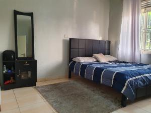 - une chambre avec un lit et un grand miroir dans l'établissement Dees shared home away from home, à Entebbe