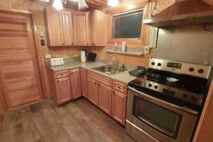 a kitchen with wooden cabinets and a stove and a sink at Riverside Cabin with Private Fishing Access! in Pulaski