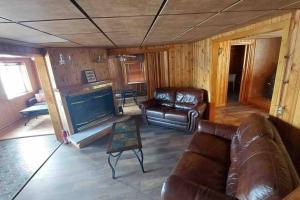 a living room with leather furniture and a fireplace at Riverside Cabin with Private Fishing Access! in Pulaski