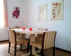 a dining room table with chairs and paintings on the wall at Ferienwohnung am Ellerbach in Hessisch Oldendorf