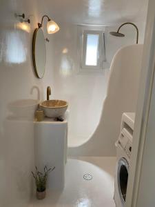 a bathroom with a sink and a washing machine at Mamos Sunset House Plaka in Plaka Milou