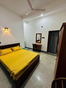 a bedroom with a yellow bed and a desk at Villa 215 in Weligama