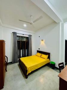 a bedroom with a yellow bed and a window at Villa 215 in Weligama