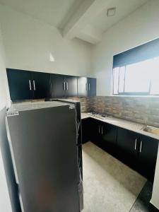 a kitchen with black cabinets and a black refrigerator at Villa 215 in Weligama +9 photos