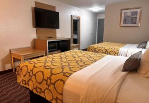 a hotel room with two beds and a flat screen tv at Baymont by Wyndham Noblesville in Noblesville +23 photos