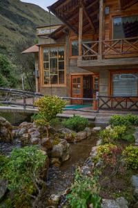 a log house with a bridge and a stream in front of it at Estancia San Juan in Cuenca