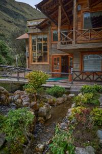 uma casa de madeira com uma ponte e um riacho à sua frente em Estancia San Juan em Cuenca