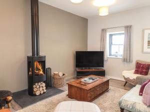 a living room with a fireplace and a tv at The Pottery in Newport Pembrokeshire