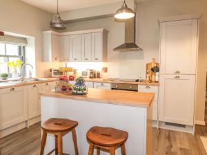 a kitchen with white cabinets and wooden stools at The Pottery in Newport Pembrokeshire