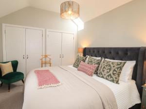 a bedroom with a large white bed with a green chair at The Pottery in Newport Pembrokeshire