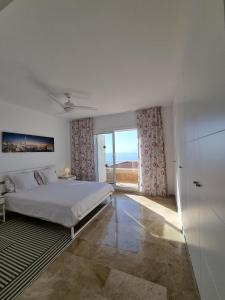 a white bedroom with a bed and a large window at VILLA LORA Modern & New townhouse 2 Bedroom in Puerto de Santiago