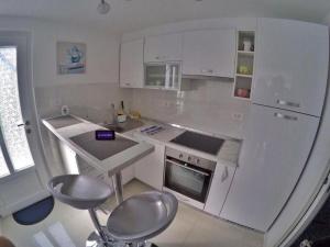a white kitchen with a counter and stools in it at Apartment By the Sea in Rabac
