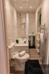 a white bathroom with a toilet and a sink at Venture Suite in Glasgow
