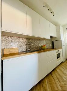 eine weiße Küche mit Holzböden und weißen Schränken in der Unterkunft Apartment Marina in Senj