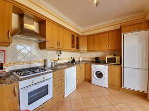 a kitchen with white appliances and wooden cabinets at Pé na Areia in Cabanas de Tavira