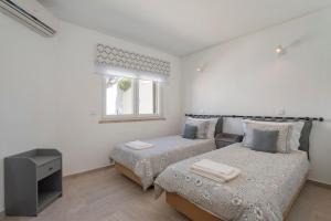a white bedroom with two beds and a window at Villa Isabel in Vale do Lobo