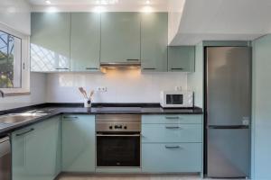 a kitchen with blue cabinets and a microwave at Villa Isabel in Vale do Lobo