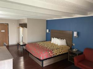 um quarto de hotel com uma cama e uma cadeira vermelha em Baymont by Wyndham Bay City em Bay City