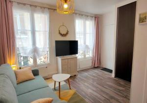 uma sala de estar com um sofá e uma televisão de ecrã plano em Le gîte entre val et rose em Provins