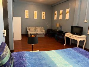 a room with a bed and a television and a couch at Herritage Piman since 1940 in San Kamphaeng