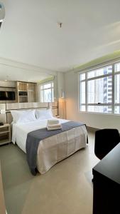 - une grande chambre avec un grand lit blanc et des fenêtres dans l'établissement Hotel Black Inn Flamboyant, à Goiânia