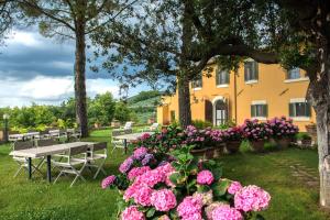 a yellow building with tables and flowers in the grass at Casa Dei Lecci in Foligno