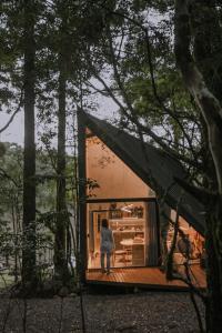 Eine Frau steht in einem winzigen Haus im Wald in der Unterkunft Arau Cabana Cheiro de Mato in Flores da Cunha