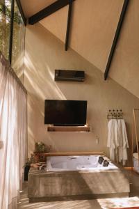 y baño con bañera grande y TV. en Arau Cabana Cheiro de Mato en Flores da Cunha