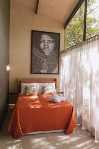 1 dormitorio con 1 cama con manta naranja y ventana en Arau Cabana Cheiro de Mato en Flores da Cunha