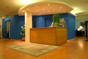a lobby with blue walls and a counter with a plant at Hotel La Vela in Passignano sul Trasimeno