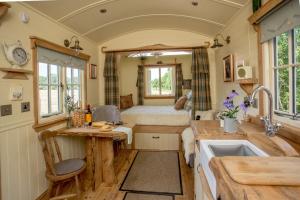 uma cozinha com uma cama e um lavatório num quarto em the abberton shepherds hut em Evesham